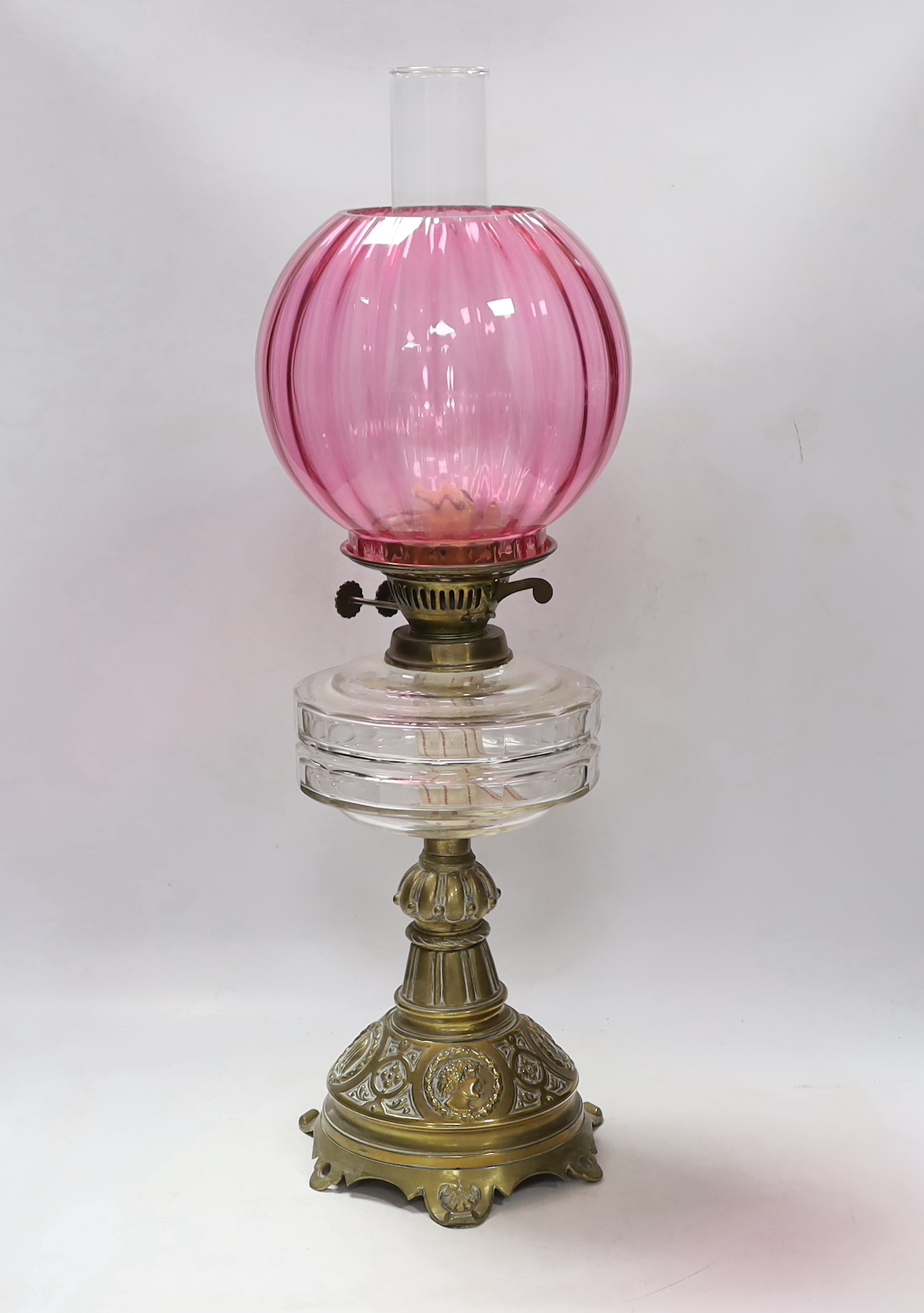 A Victorian brass based oil lamp, with cranberry glass shade, 58cm high